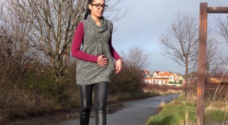 Short taken girl Esperansa pulls down her leather pants to pee by a bike path