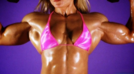 Blonda kroppsbyggaren Brigita Brezovac pumpar järn i en rosa bikini