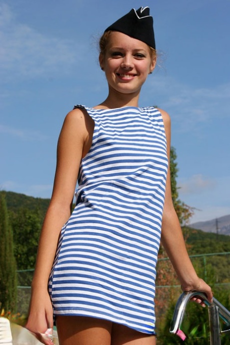 Cute teen flashes her underwear next to a swimming pool while wearing a cap