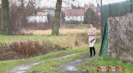 La chica de la espera Eveline Neill se pone en cuclillas para orinar mientras da un paseo por un camino mojado