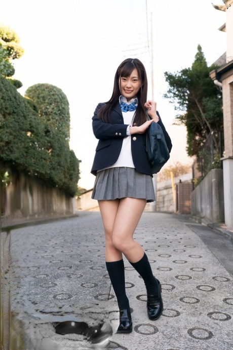 Японская школьница демонстрирует нижнее белье под юбкой, а затем раздевается до носков