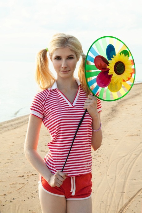 De kleine blonde tiener Candy toont haar poesje in haar blootje op een strandlaken