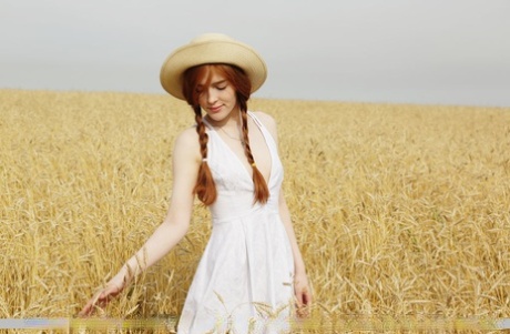 De jonge roodharige Jia Lissa kleedt zich uit tijdens een picknick in een haverveld