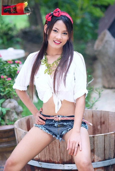 La sexy ragazza thailandese Ya Soraya si spoglia sul bordo di una vasca di legno