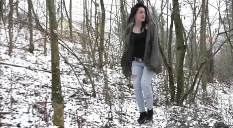 Brunette chick Selena pist op besneeuwde grond in het bos