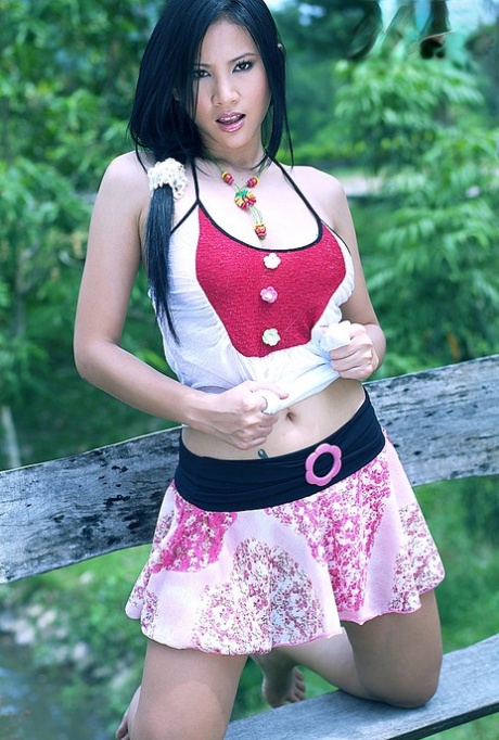 Den vakre thailandske jenta Nancy Ho kler av seg på en rustikk hagebenk.