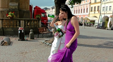 Des femmes ivres en robe de mariée font un combat de chats dans une rue pavée.