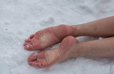 裸の赤毛の奴隷は、冬の雪の中で屋外に縛られ、冷たい裸のつま先を曲げます。