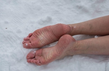 Escrava ruiva nua, presa ao ar livre na neve do inverno, flexionando os dedos dos pés nus e frios