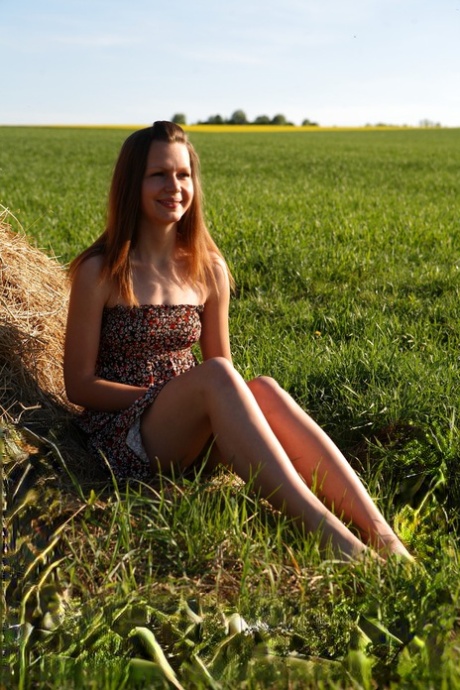 Young girl has sex with a boy against a pile of weathered hay in a field