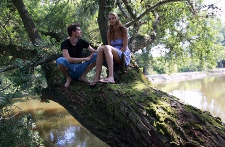 Ungt par har samlag på en trädgren över vattnet