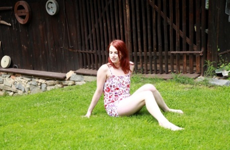 Den unge, naturlige rødhårede Jarmila onanerer på en gressplen i bar overkropp.