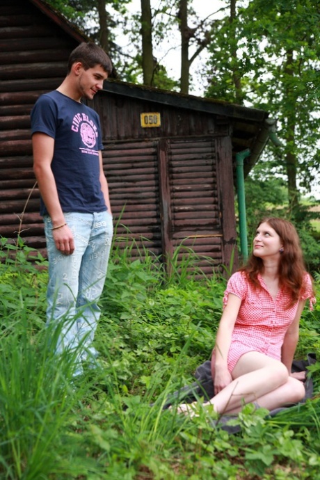 Junge Rothaarige und ihr Freund haben Sex außerhalb einer Hütte im Wald