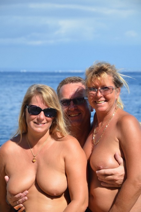 To blonde kvinder med hængebryster nyder frækt sutteri og knepperi i strandtrekant