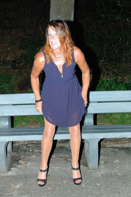 Mujer amateur se baja la manguera para mear en un banco del parque por la noche