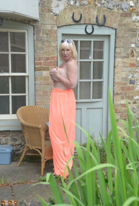 Big titted blonde Melody drops her dress outside to air her naked mature tits