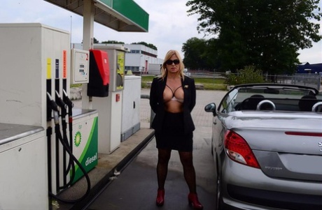 Oudere blonde naakte Chrissy toont zichzelf terwijl ze tankt bij een benzinestation