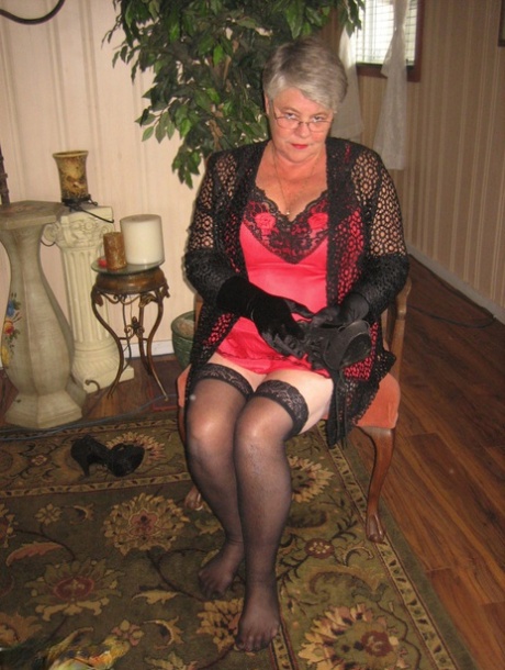 Oude dame Girdle Goddess doet lingerie uit om naakt te poseren in kousen en handschoenen
