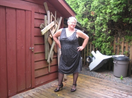 Dikke oma Girdle Goddess laat haar grote borsten los naast een dichtgetimmerd gebouw