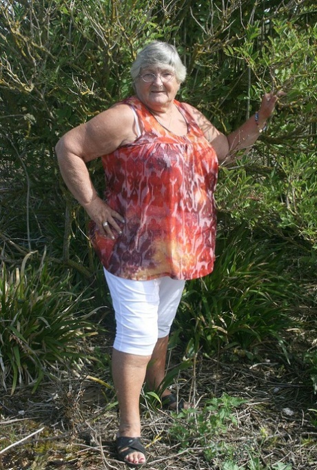Zwaarlijvige oma Libby stript helemaal naakt bij groenblijvende bomen