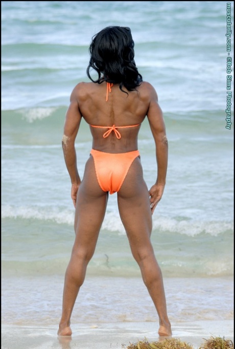 Ebony bodybuilder Debra Dunn poserar vid havet i en stringbikini