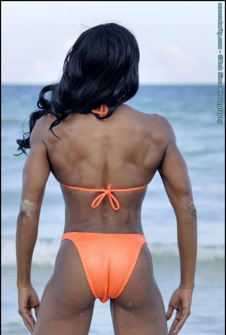 Ebony bodybuilder Debra Dunn poses at the ocean in a string bikini