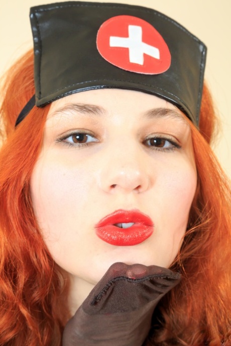 Redhead in latex nurse attire pulls on pantyhose all over her body