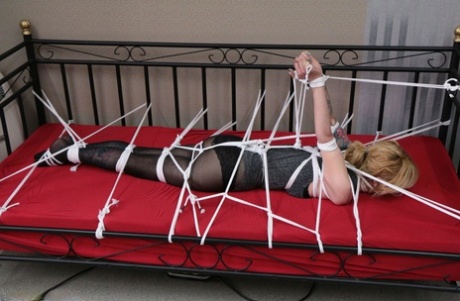 Solo girl is left face down on a daybed while tied up with rope