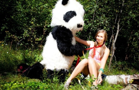 Junges Mädchen Penny wird von einem Panda auf einem Felsen in der Nähe des Waldes geknallt