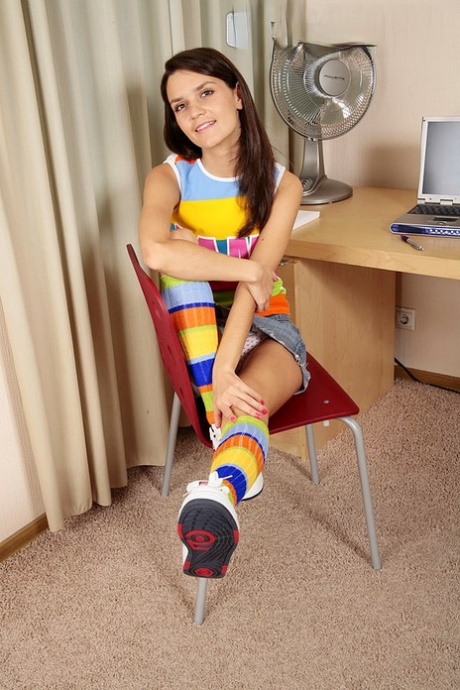 La fille solitaire Dasha se dénude dans des chaussettes et des baskets multicolores.