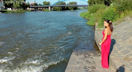 Vollbusige Brünette in rotem Kleid und exotischem Höschen geht im örtlichen Fluss schwimmen