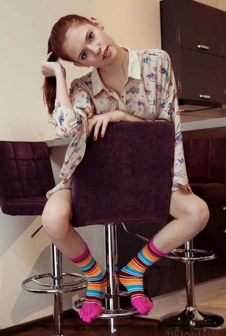 De jonge roodharige Juliett Lea toont haar roze poesje na het strippen op sokken