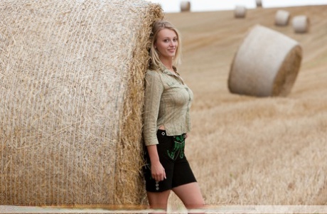 Beautiful blonde teen Carisha strips naked next to a round bale of hay