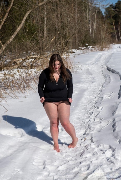 Brunette BBW entledigt sich des Ballknebels und der Seile, während sie nackt und barfuß im Schnee posiert