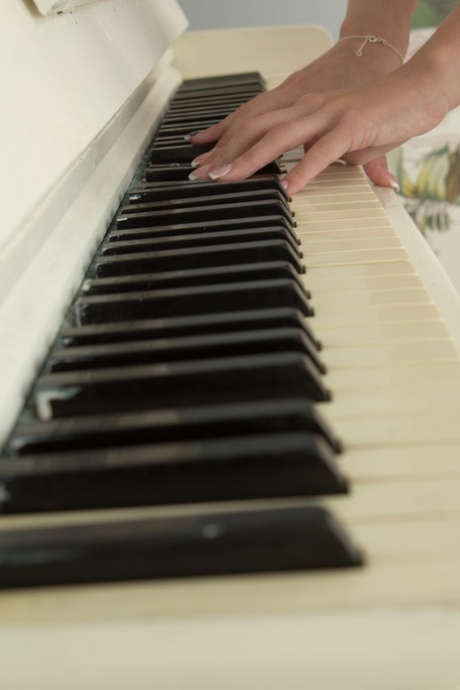 Schattige blonde tiener Linet neukt vingers boven op een staande piano