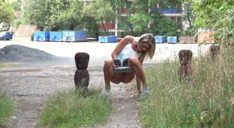 Blonde girl Claudia Macc takes a piss on a walking path during the day