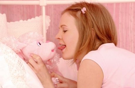 Young looking girl Mona hugs a stuffed animal while masturbating on her bed