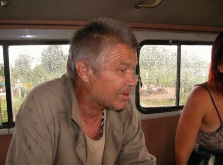Ung rødhåret kvinde sætter kondom på en gammel hjemløs mand og knepper ham i en varevogn