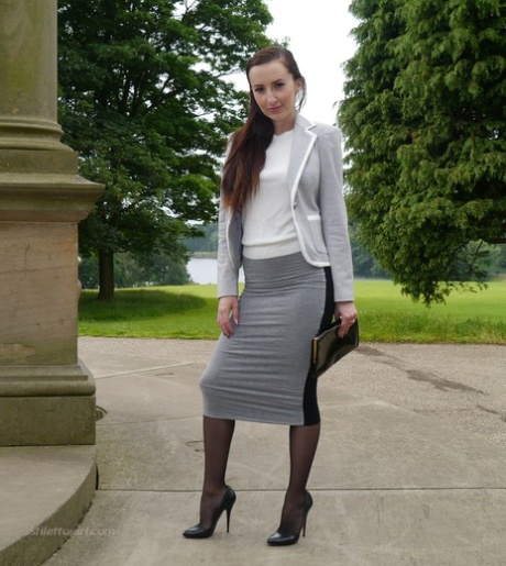 Clothed woman Sophia descends park steps in a long skirt and stiletto heels