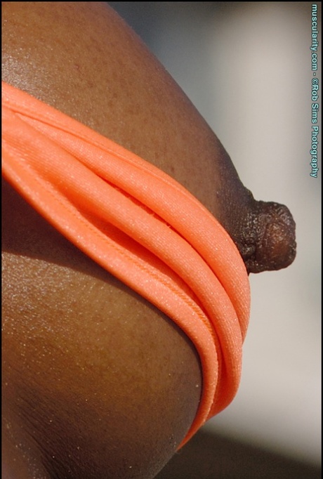 A fisiculturista de ébano Victoria Dominguez deixa as suas mamas livres de um biquíni numa praia