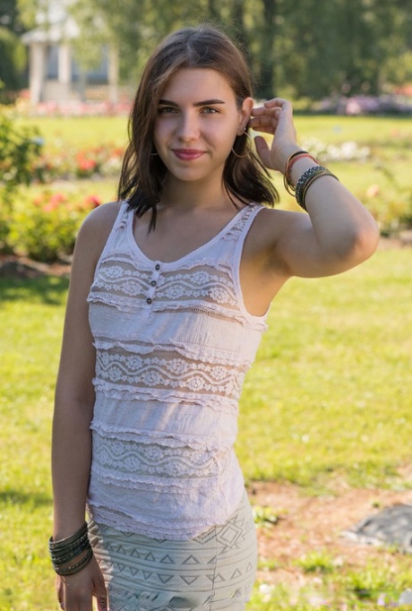 Jonge brunette Zhenya Mille kleedt zich uit voor naakt poses op picknick tafel