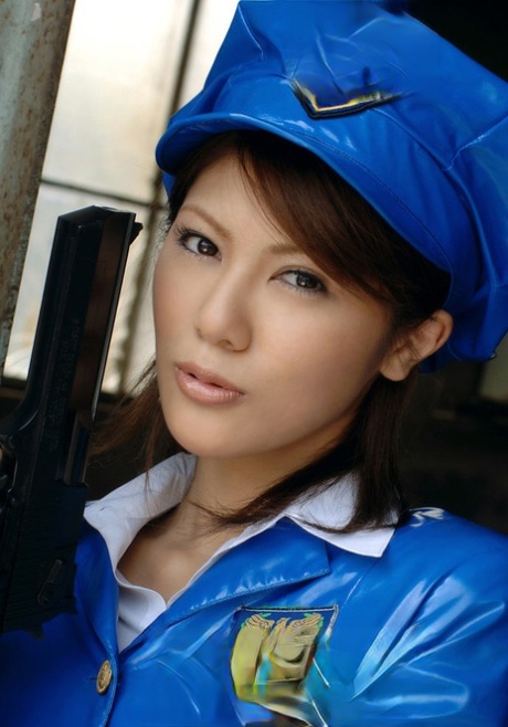 Die asiatische Polizistin Anna schwingt eine Pistole in einem kurzen Latexrock und Strumpfhosen