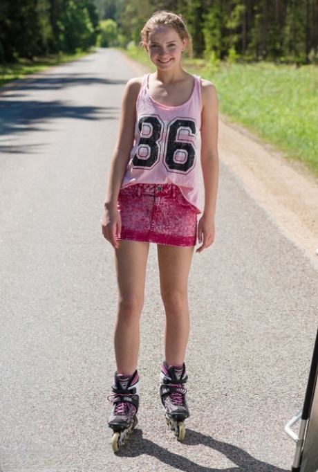 Den unge blonde pige Faina står nøgen midt på vejen på rulleskøjter