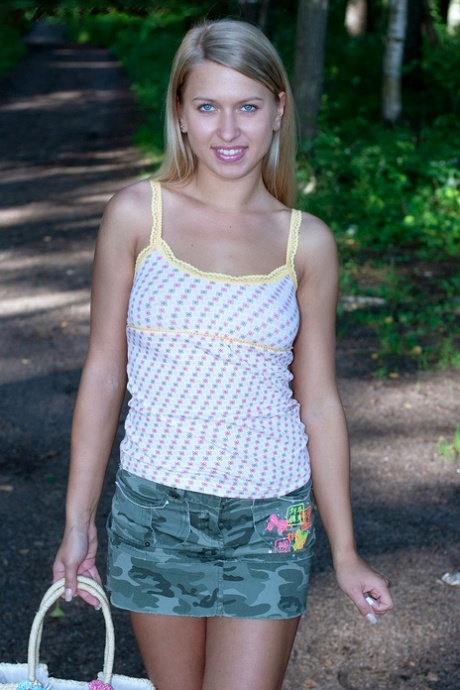 Blonde amateur Riana walks into the woods before showing her tits and ass