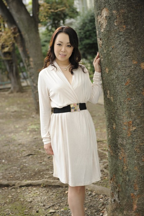 Элегантная японка Юна Ямами в белом платье моделирует обнаженную фигуру на открытом воздухе