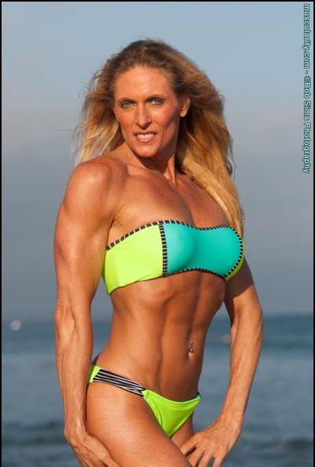 Vrouwelijke bodybuilder Kimberly Dickson poseert in bikini op het strand