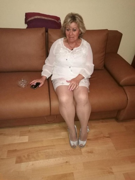 Mature lady exposes her large tits while having a smoke in pantyhose