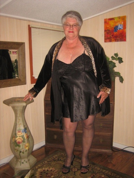 Donna grassa e anziana Dea della cintura si spoglia della lingerie nera per posare nuda con le calze