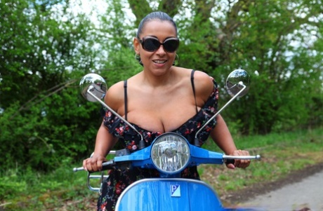 Mature lady Danica Collins exposes large tits and twat on a scooter