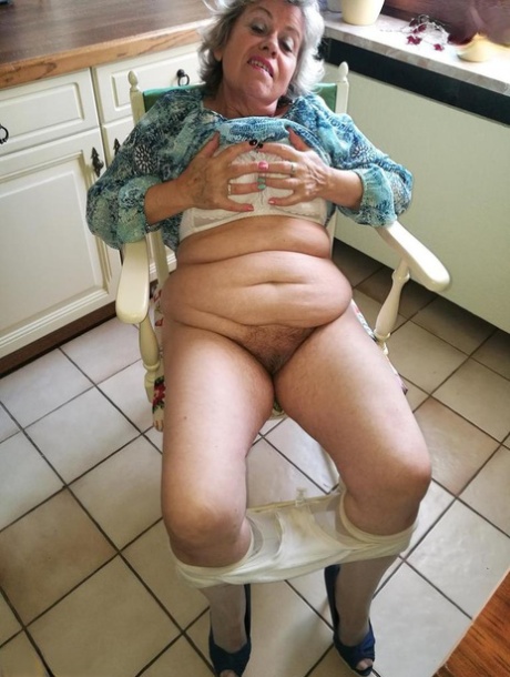 La abuelita cachonda Caro se mete un plátano en su coño natural en la silla de la cocina